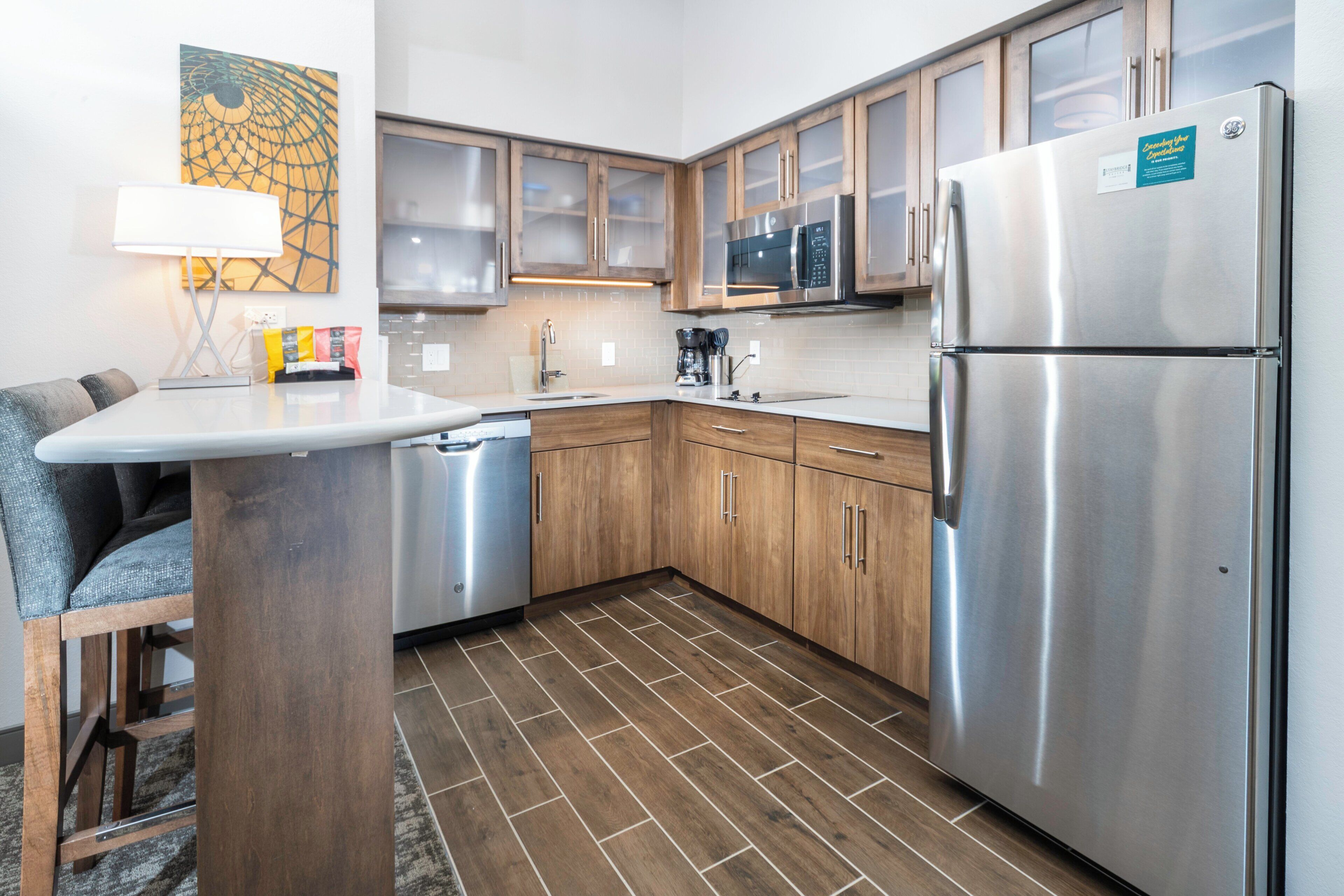 A compact kitchen with a refrigerator, microwave, and wooden cabinets.