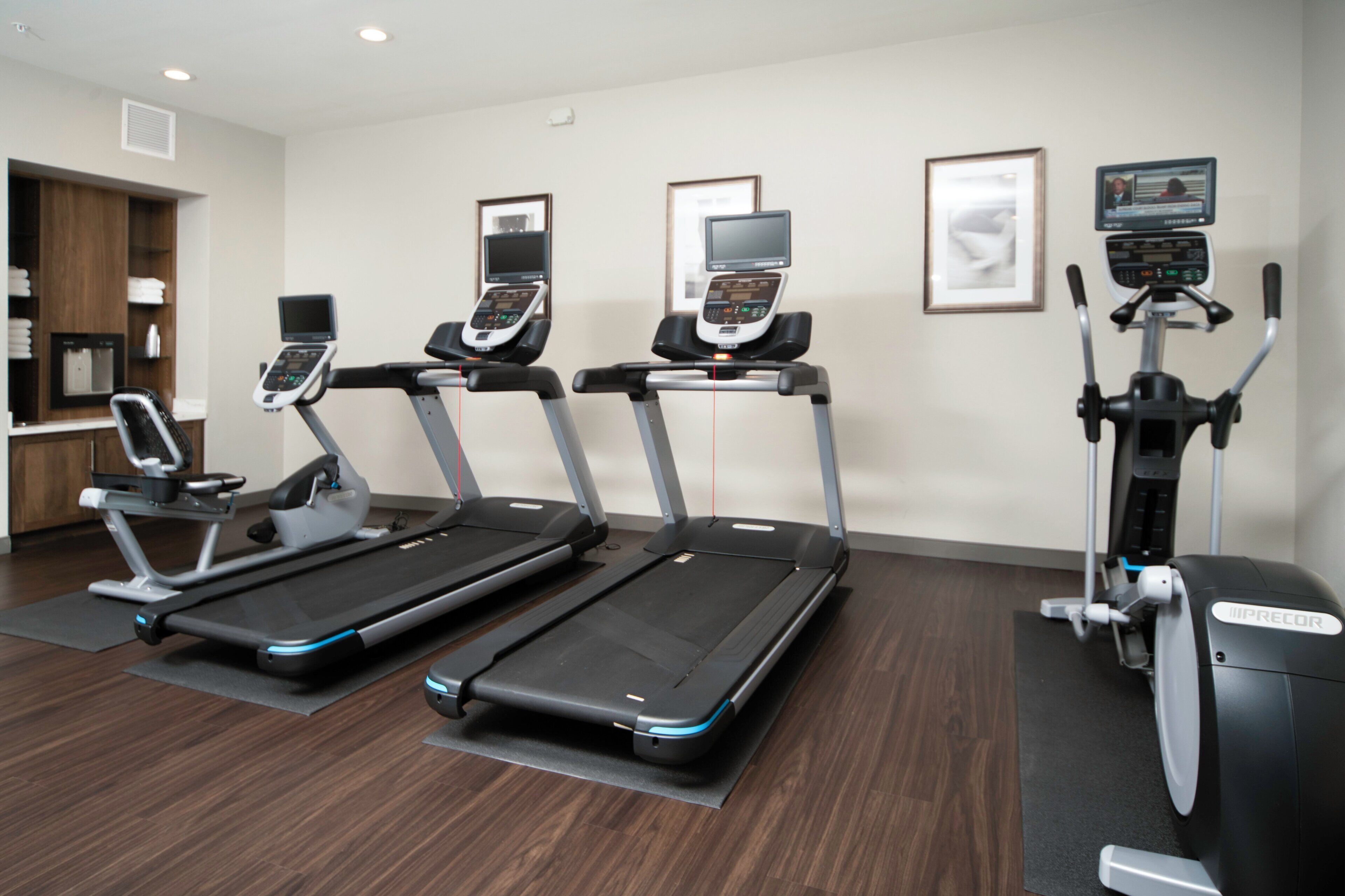 A fitness center with treadmills, an elliptical, and a stationary bike, all equipped with digital displays.