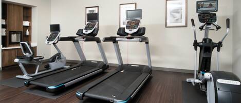 A fitness center with treadmills, an elliptical, and a stationary bike, all equipped with digital displays.