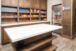 Un espace cuisine doté de meubles en bois, d’un plan de travail en marbre et d’un garde-manger.
