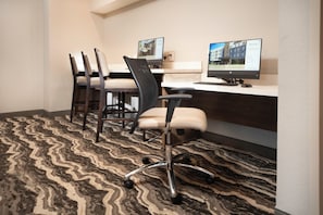 Une chambre d’hôtel équipée d’un bureau, de deux chaises, d’un ordinateur et d’un tapis à motifs.