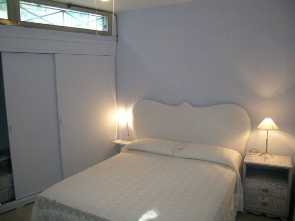 A bedroom with a bed, nightstands, a wardrobe, and a window.