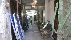 A stone-walled entrance with a glass door, a star-shaped light fixture, and wicker furniture outside. - Silvia (Capoliveri)