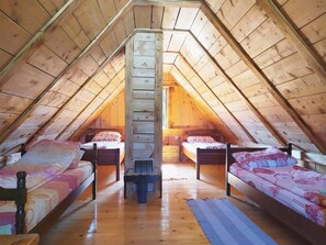 A cozy attic bedroom with wooden beams, two single beds, a central bench, and a staircase. - Summit Guest House & Grill (Kabati)