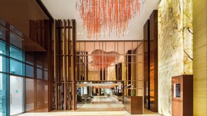 Een moderne hotel lobby met een ruime indeling, een receptiebalie en een decoratieve hanglamp.