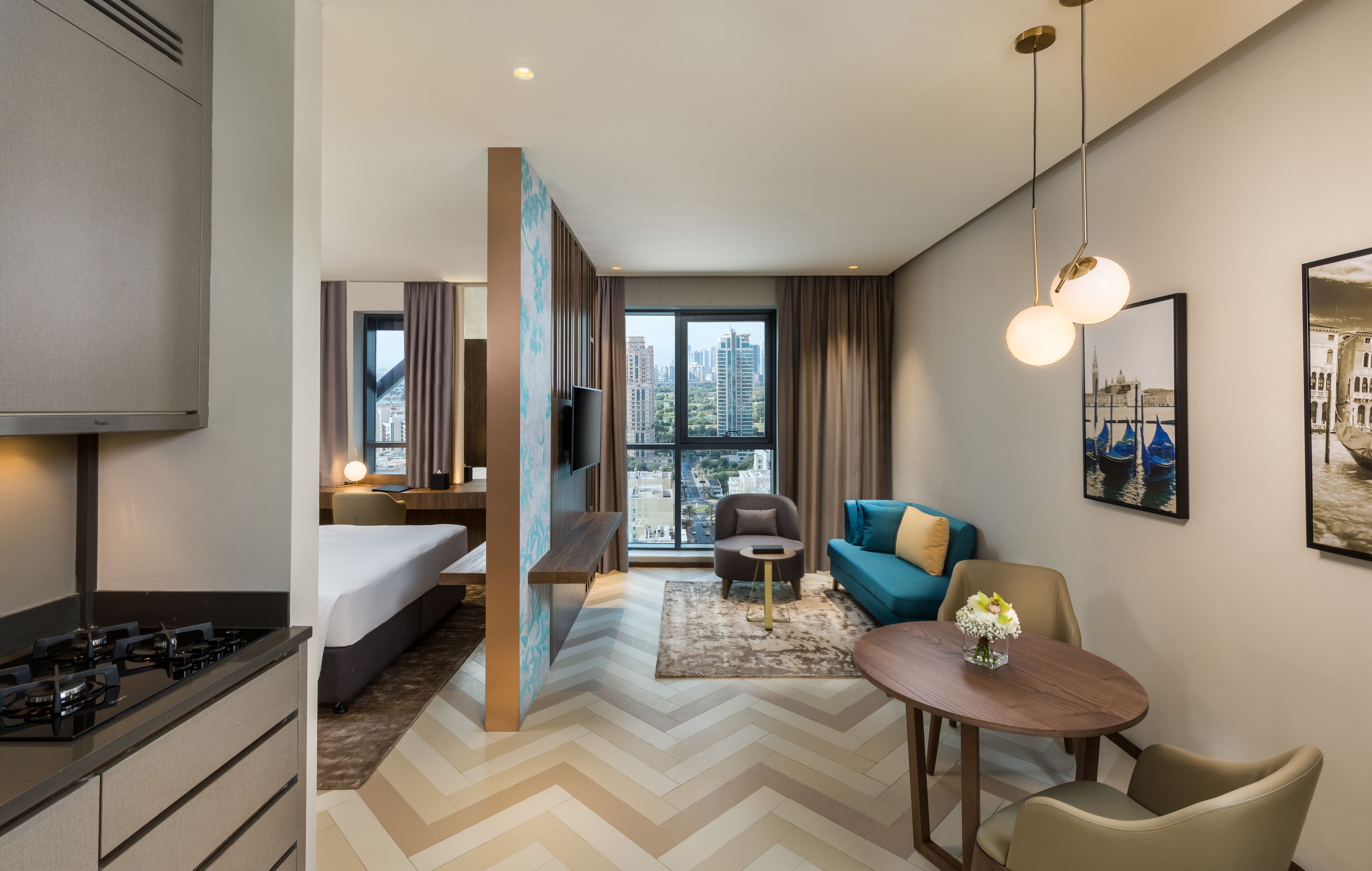 A hotel room with a bed, a desk, a TV, a dining table, and a view of the cityscape.