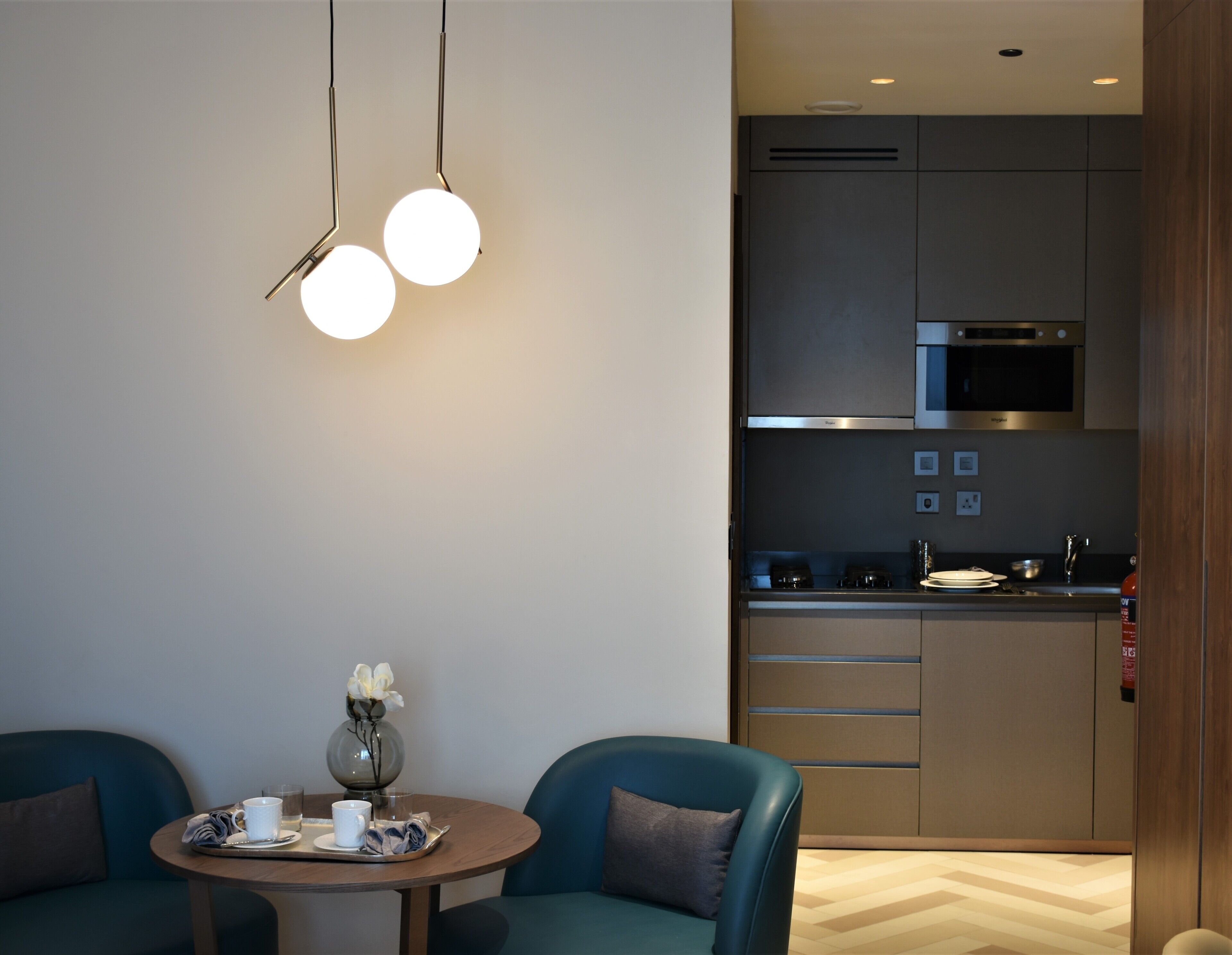 Una cocina moderna con electrodomésticos de acero inoxidable, un comedor con una mesa redonda y dos sillas azules.