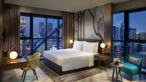 Een moderne hotelkamer met een groot bed, een bureau, een stoel en uitzicht op de stad.