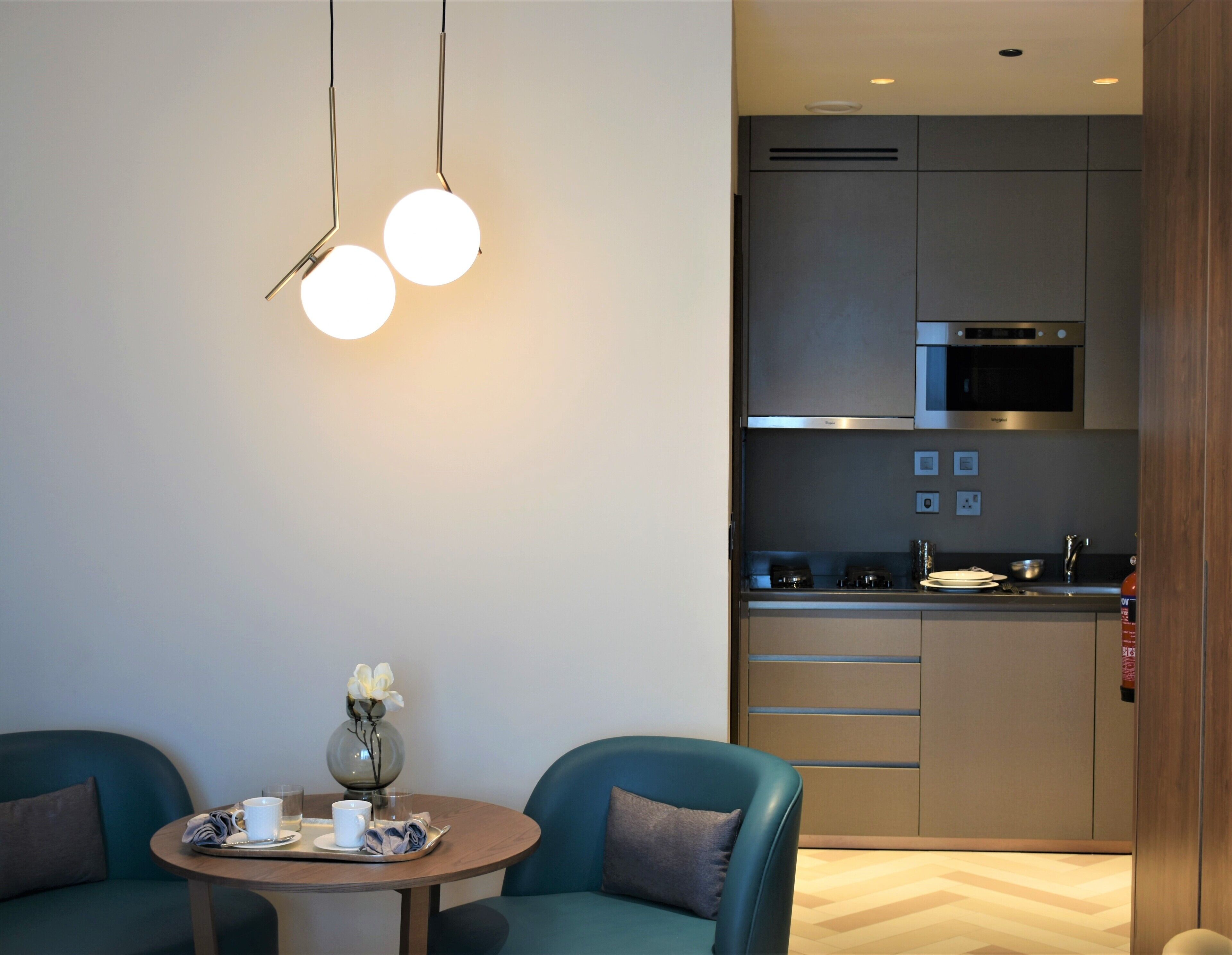 Una cocina moderna con electrodomésticos de acero inoxidable, un comedor con una mesa redonda y sillas, y un jarrón con flores sobre la mesa.