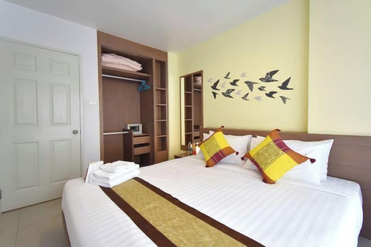 A hotel room with a large bed, a wardrobe, and a wall decoration of birds.
