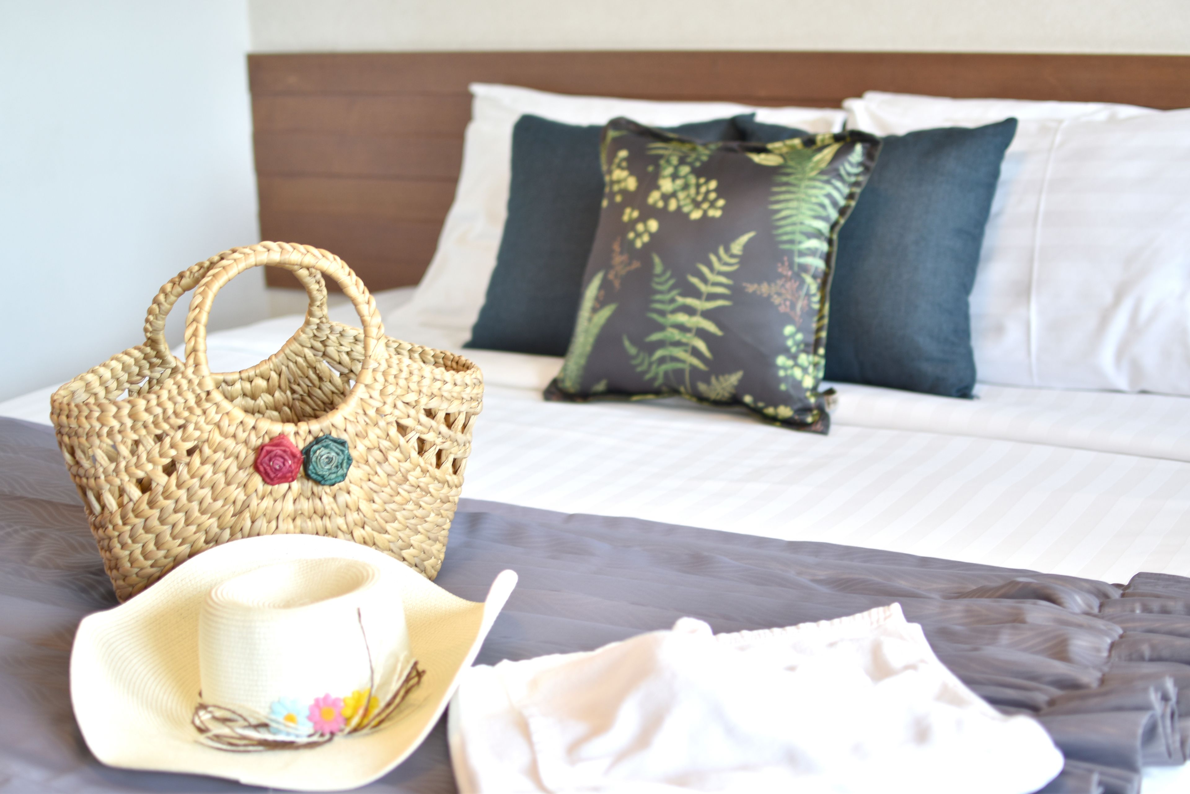 A bed with a woven basket, a straw hat, and a white cloth on a bedspread.