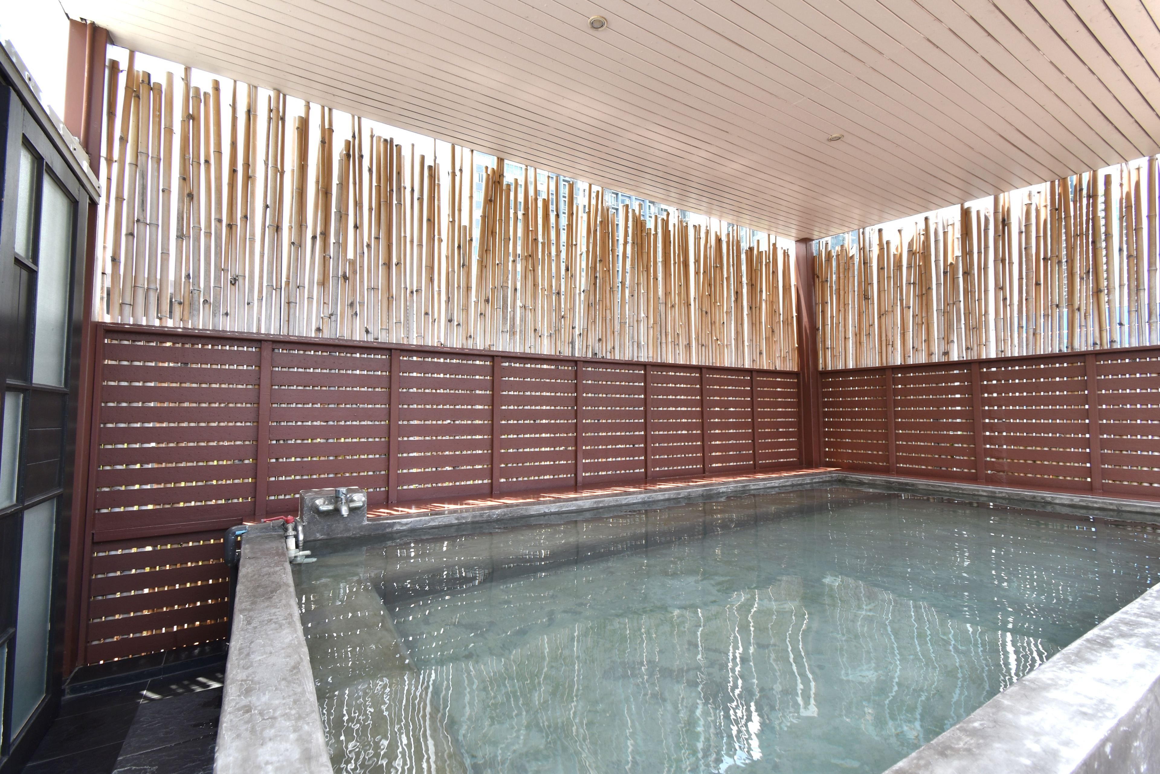 Ein Wellnessbereich mit großem rechteckigen Pool, Holzschindeln und gefliestem Boden.