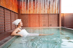 A person relaxing in a clear indoor pool with wooden slatted walls and a tiled floor. - Ascella Sukhumvit 38 (Bangkok)