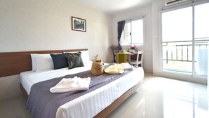 Una camera d'albergo con un letto, una scrivania e un balcone.