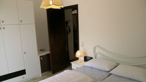 Una camera da letto con due letti, un comodino con una lampada, un armadio e uno specchio.