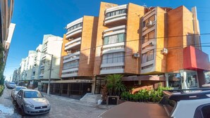 Un edificio de varios pisos con un diseño arquitectónico moderno, con balcones y unidades de aire acondicionado.