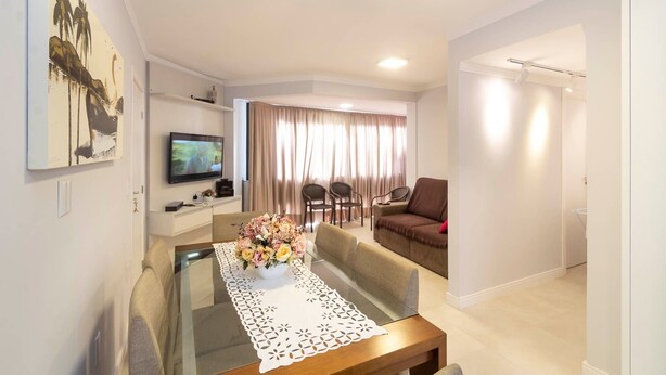 Una sala de estar moderna con una mesa de comedor de vidrio, un sofá, un televisor y un cuadro en la pared.