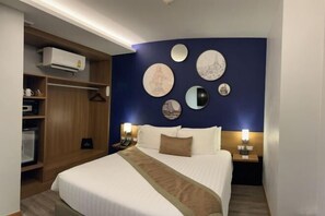 A hotel room with a bed, bedside tables, a wardrobe, and wall decor. - Aspira One Sutthisan (Bangkok)