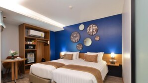 A hotel room with two beds, a desk, a wardrobe, and decorative wall art. - Aspira One Sutthisan (Bangkok)