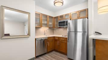 A modern kitchen with wooden cabinets, stainless steel appliances, and a built-in dishwasher.