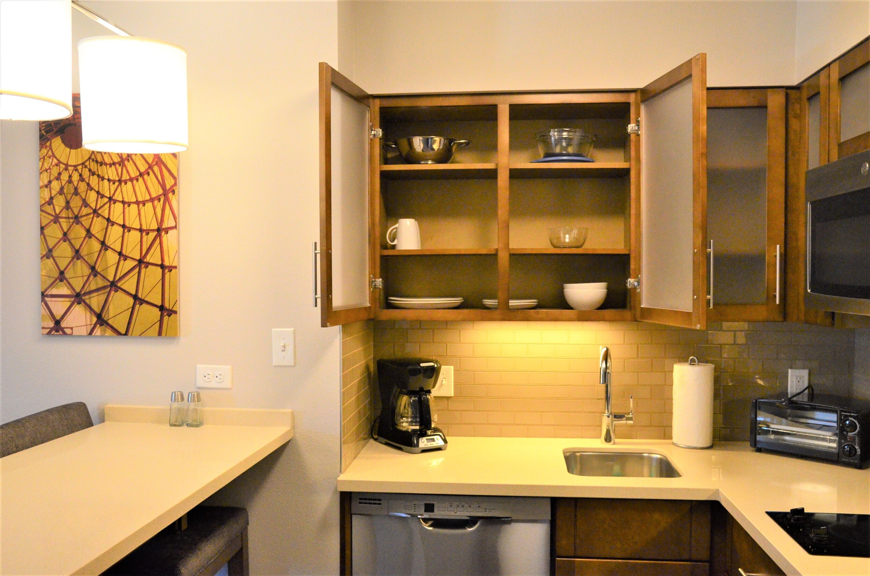 A compact kitchen with wooden cabinets, a coffee maker, a toaster, and a sink.