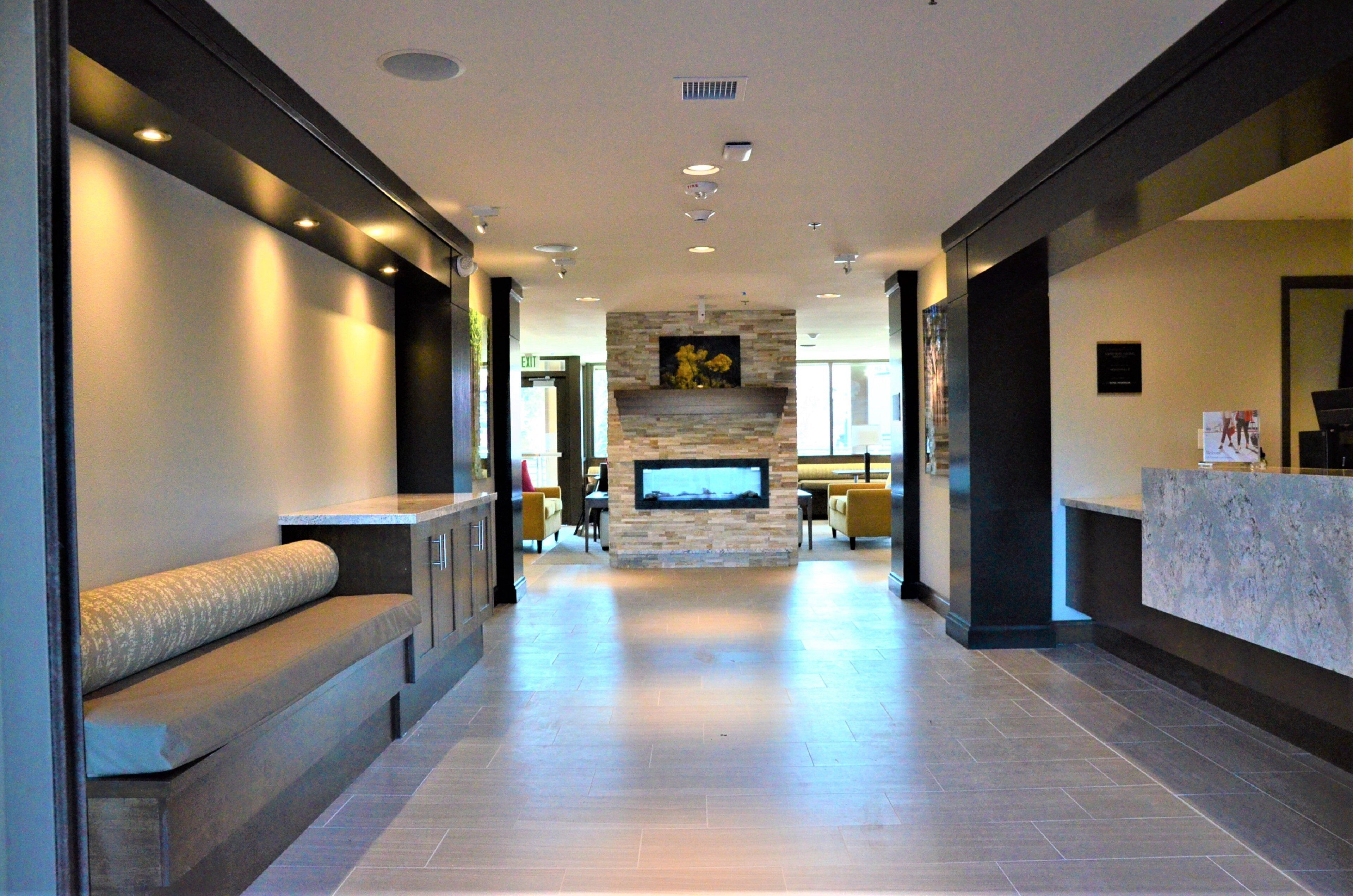Un hall de hotel con mostrador de recepción, zona de estar y chimenea de piedra.