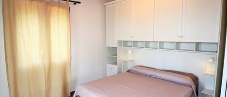 A bedroom with a bed, a wardrobe, and a curtain.