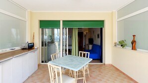 A small, enclosed patio area with a table and chairs, a counter, and a sliding door leading to an adjacent room. - VerdeBlu (Capoliveri)