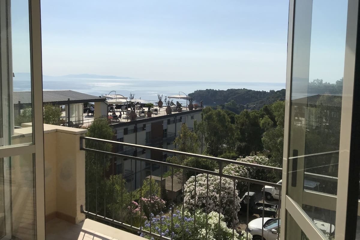 A balcony with a view of a coastal area, including buildings and a body of water.