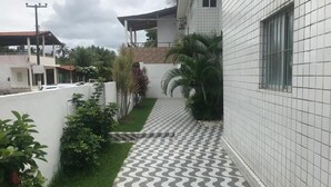 Un estrecho sendero con baldosas decorativas que conduce a un edificio con paredes de azulejos blancos y una ventana.