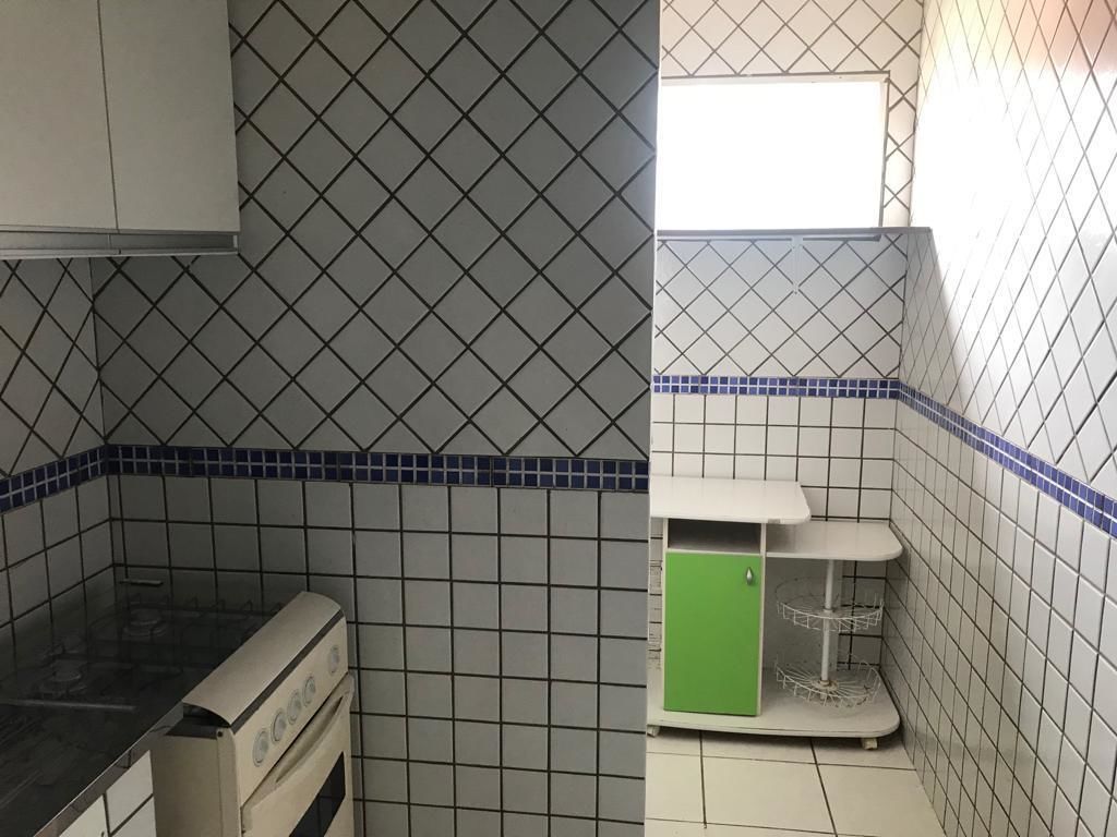 Eine Küche mit Gaskochfeld, einem grünen Schrank und einer gefliesten Spritzschutzwand.