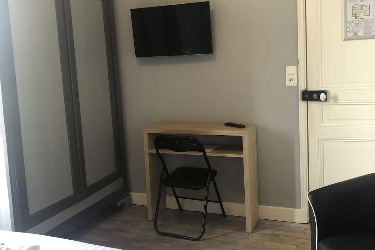 Ein Hotelzimmer mit Bett, Schreibtisch, Stuhl, Fernseher und Kleiderschrank.