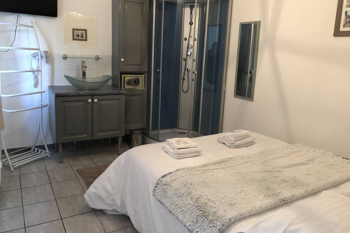 Ein modernes Badezimmer mit einer Duschkabine, einem integrierten Waschbecken und einem Handtuchhalter.