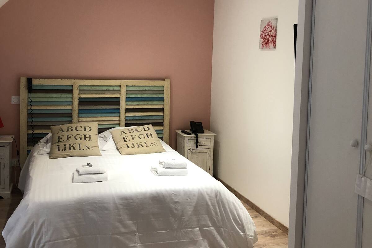 Ein Schlafzimmer mit einem Bett, einem Nachttisch, einem Holz-Kopfteil und einer Tür.