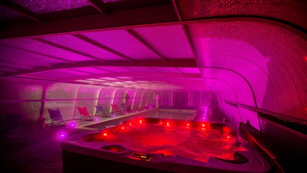 A hot tub with a digital control panel, surrounded by lounge chairs and a ceiling with a unique geometric design. - Chemin des Dames Le Relais De Fleurette (Pontavert)
