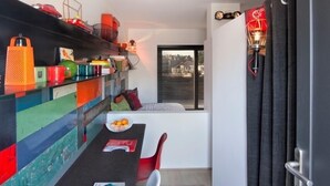 A modern kitchen with a colorful backsplash, a dining area with a table and chairs, and a view of the city through the window.