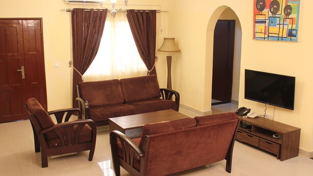 A living room with a sofa, two armchairs, a coffee table, a TV, and a small cabinet. - Riverside Resort Villas (Bushrod Island)