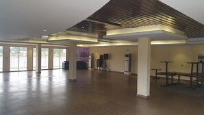 A spacious indoor area with a high ceiling, large windows, and a stage with audio equipment. - Riverside Resort Villas (Bushrod Island)