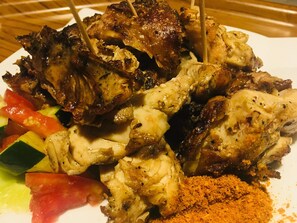 A plate of grilled chicken skewers with vegetables and a sprinkle of seasoning.