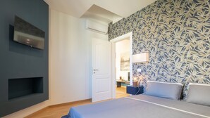 Ein Schlafzimmer mit einem Bett, einem an der Wand montierten Fernseher, einer Tür und einer Wandtapete mit Muster.