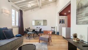 Ein modernes Wohnzimmer mit einer Couch, einem Esstisch, Stühlen und einer Küche im Hintergrund.