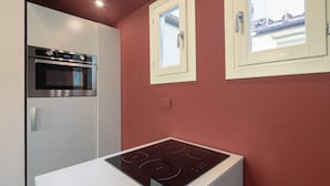 Eine kleine Küche mit Einbauofen, Kochfeld und Fenster mit Zugang.