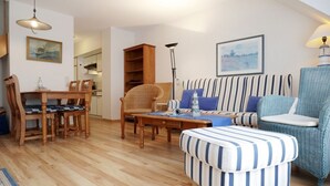 Una sala de estar con una mesa de comedor, sillas, un sofá, un reposapiés a rayas y una lámpara.