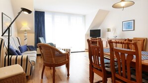 Una sala de estar con sofá, sillas, una mesa de comedor y un televisor.