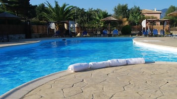 Una piscina al aire libre, sombrillas, sillones reclinables de piscina