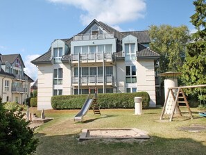 A multi-story residential building with a balcony, a slide, and a swing set in the yard. - Seestern Whg. 4/50, Germany (Ostseebad Boltenhagen)