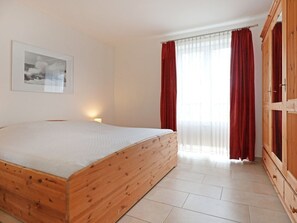 A bedroom with a wooden bed, a wardrobe, and a window with red curtains. - Seestern Whg. 4/50, Germany (Ostseebad Boltenhagen)