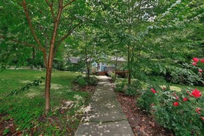 A garden pathway leading to a house with a porch.