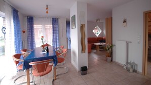 Un comedor con una mesa y sillas, un sofá y un ventanal con cortinas.