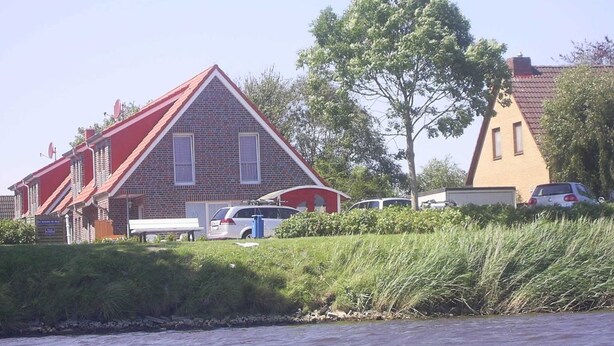 Un edificio con techo rojo y paredes de ladrillo, junto a una masa de agua.